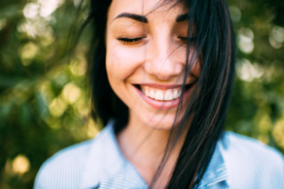 long dark hair and perfect smile with closed eyes on the green background