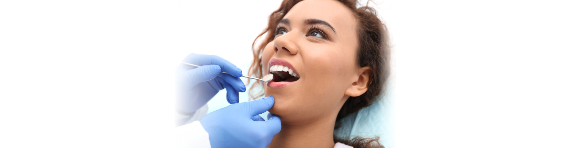 Dentist examining African-American woman`s teeth with mirror